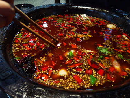 Closeup of Chinese spicy soup with chicken and vegetables in a hot potの写真素材