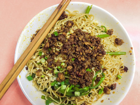 Noodles with minced meat and green onions in a plate on a pink backgroundの写真素材