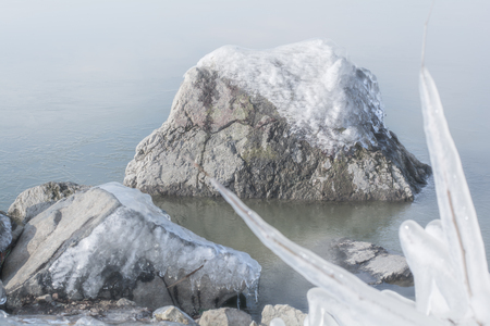 Frozen rocks with ice in the winter pondの写真素材