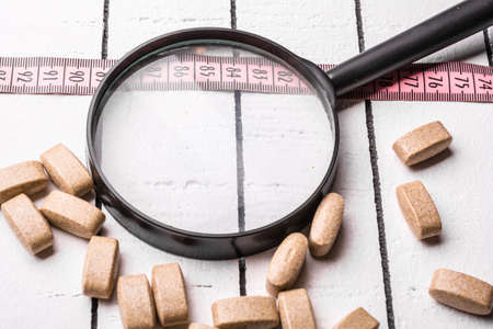 Pills and pink centimeter over the white backgroundの写真素材