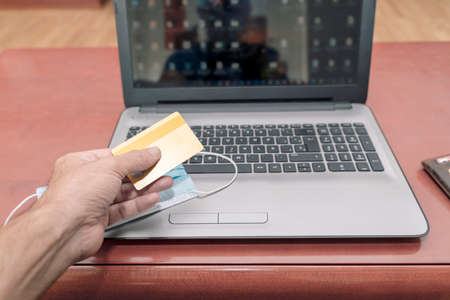 Man's hands holding a credit card and using an online computer to make a purchase or payment through the internet. Online shopping and online banking concept.の写真素材