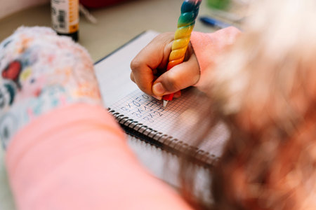 detail of a young girl solving elementary school math problems at home. Concept of online education.