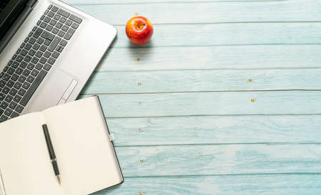 top view of a workspace with laptop computer idea notebook and pen, with a red apple on a blue vintage wooden table. Business concept.の写真素材