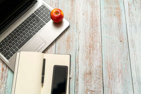telephone, computer, notebook, red apple on a vintage wooden table. top viewの写真素材