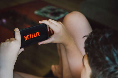 Zaragoza, Spain - 23 June 2021: Teenager with smartphone opens Netflix appのeditorial素材