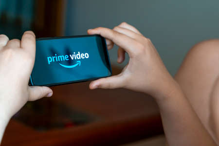 Zaragoza, Spain - 23 June 2021: a teenager with a smartphone opens Amazon video applicationのeditorial素材