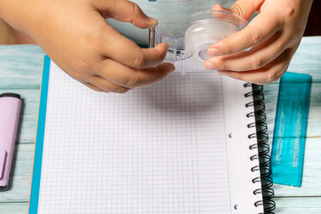 Hands of a girl playing with a toy puzzle cube on a table with school objects such as a notebook, glasses and scissors. Concept of solving difficult tasks or intelligence.の写真素材