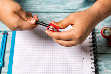 Hands of a girl playing with a toy puzzle cube on a table with school objects such as a notebook, glasses and scissors. Concept of solving difficult tasks or intelligence.の写真素材