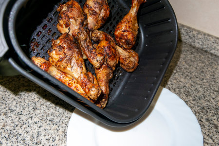 close-up of the basket of an air fryer with crispy roasted chicken legsの写真素材