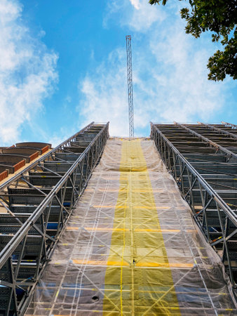 Shot from below a crane of a building under construction with scaffolding and a clear blue sky.の写真素材