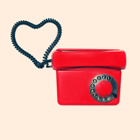 Red old retro rotary phone with heart shape of wire, vintage colors photoの写真素材