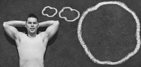 Sport, fitness and healthy lifestyle concept - handsome confident sportsman relaxing and thinking on the ground with painted clouds, top viewの写真素材