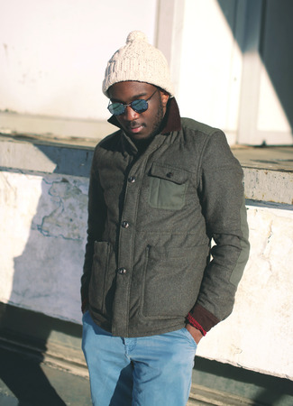 Fashion stylish young african man wearing a sunglasses and jacket with knitted hat in cityの写真素材