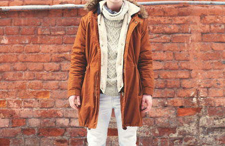 Fashion man in warm brown jacket posing on a textured brick wall backgroundの写真素材