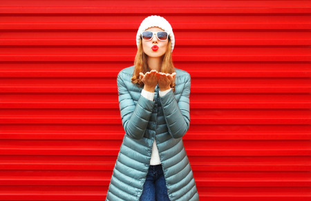 Fashion pretty woman is blowing red lips sends an air kiss on a backgroundの写真素材