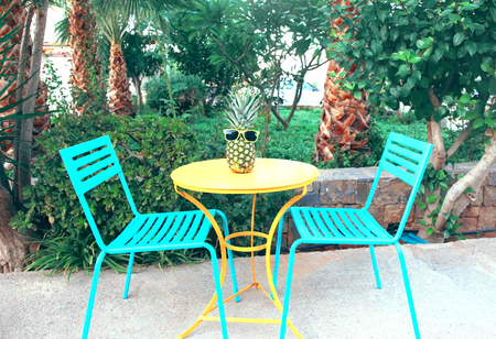 Fashion pineapple in a sunglasses on the table outdoors, summer holidays, vacation and food conceptの写真素材