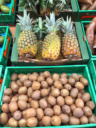 Kiwi and pineapples fruits in the boxes close-upの写真素材