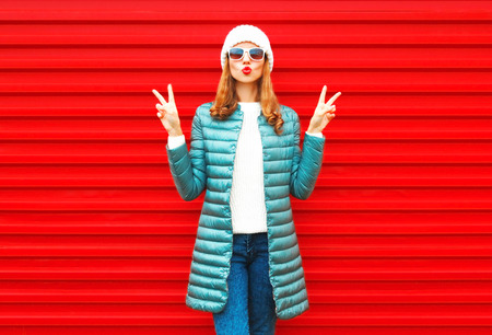 Fashion pretty woman blowing red lips doing air kiss posing on a backgroundの写真素材