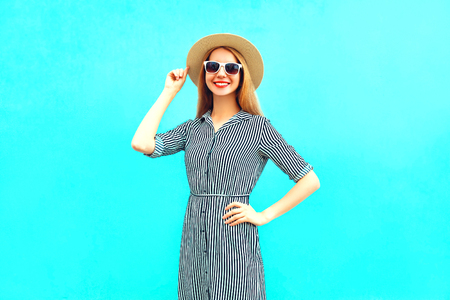 Fashion young smiling woman in striped dress on a blue backgroundの写真素材