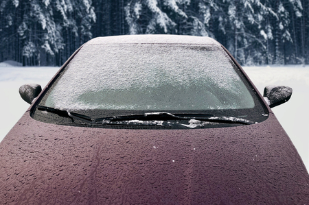 Frozen winter car covered snow, view front window windshield and hood on snowy backgroundの写真素材