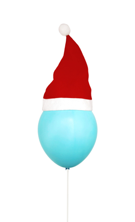 Funny blue air helium balloon with red christmas santa hat isolated on white backgroundの写真素材
