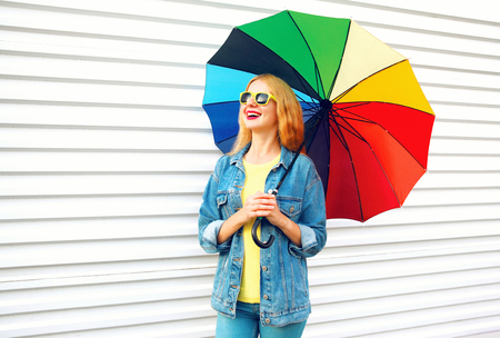 Happy woman laughing holds colorful umbrella, dreams on white backgroundの写真素材