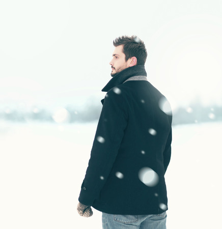 Fashion elegant free man in winter snowstorm looks away, view profile, flying snowflakesの写真素材