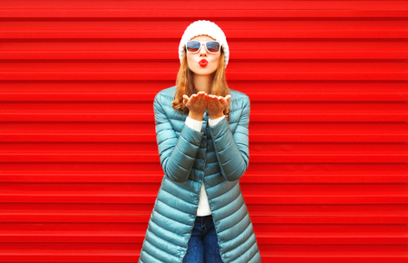 Fashion pretty woman is blowing red lips sends an air kiss on a backgroundの写真素材