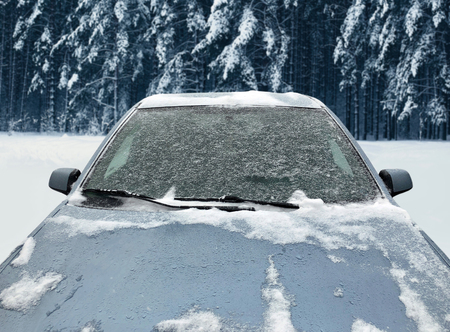 Frozen winter car covered snow, view front window windshield and hood on snowy backgroundの写真素材