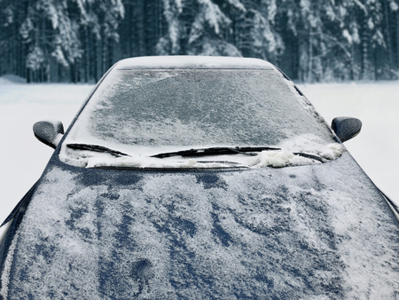 Frozen winter car covered snow, view front window windshield and hood on snowy backgroundの写真素材