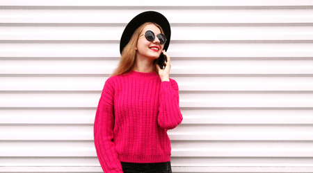 Portrait happy smiling young woman calling on smartphone on city white wall backgroundの写真素材