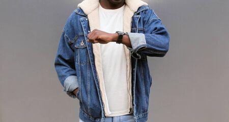 Close up african man looking at smart watch using voice assistant or takes calling on gray backgroundの写真素材