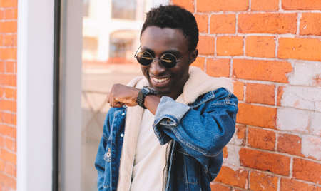Portrait close up happy smiling african man with smart watch using voice command recorder or takes calling on a city streetの写真素材
