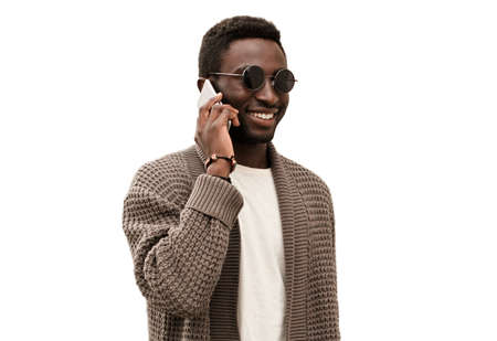 Portrait of smiling young african man talking on a smartphone isolated on a white backgroundの写真素材