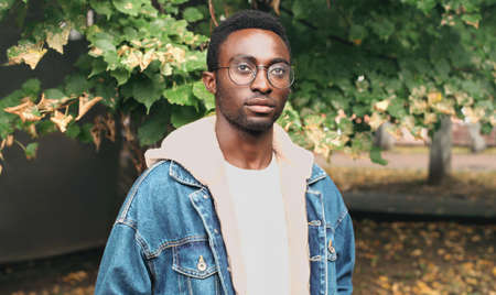 Portrait of young african man wearing eyeglasses in autumn city parkの写真素材