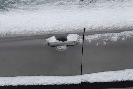 Close up frozen winter car covered snow, view side door with locked door handleの写真素材