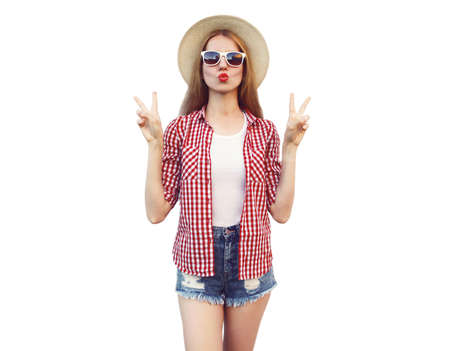 Stylish portrait of beautiful woman blowing her lips sending sweet air kiss wearing a summer straw hat isolated on white backgroundの写真素材