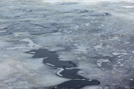 Cracked ice floes on a frozen sea, winter cold background, aerial top view waterの写真素材