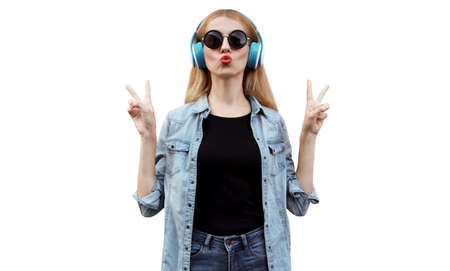 Portrait of young woman listening to music in headphones blowing her red lips isolated on white backgroundの写真素材