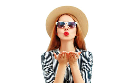 Portrait of beautiful young woman blowing her red lips wearing a striped dress, summer straw hat isolated on white backgroundの写真素材