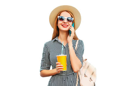 Portrait of happy smiling woman calling on smartphone with cup of juice wearing straw hat, backpack isolated on white backgroundの写真素材