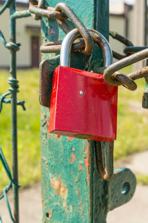 Red closed padlock on the chain on the gate.