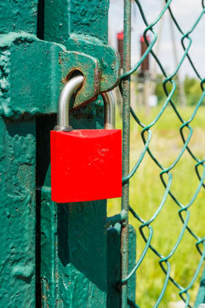 Red closed padlock on the green gateの写真素材