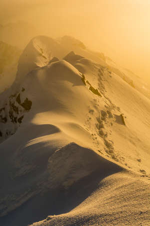 Fog clouds at sunrise on the ridge in the winter in the mountains.の写真素材