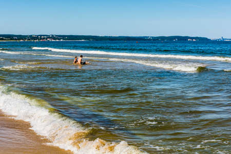 Gdansk, Poland - June 7, 2016: Two friends sitting in the water in the Baltic Sea.のeditorial素材