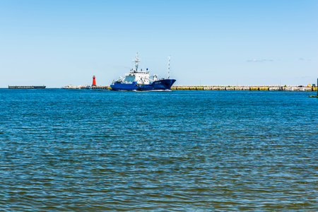 Gdansk, Poland - June 7, 2016: Ship affecting port flows past the lighthouse.のeditorial素材