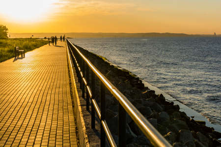 Gdansk, Poland - June 7, 2016: Walkers on the promenade by the Baltic Sea in the setting sun.のeditorial素材