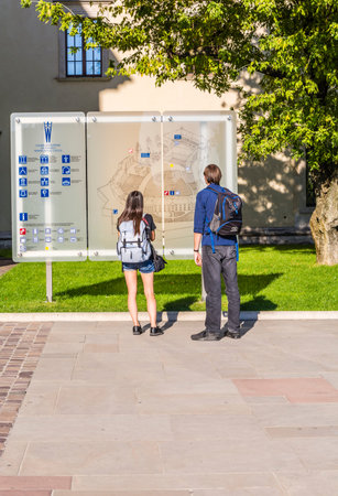 Krakow, Poland - August  26, 2016: Tourists look at the information board Wawel Castle in Krakow.