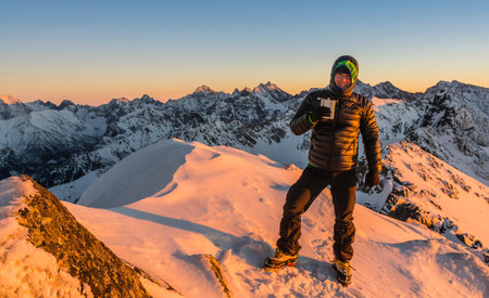 Tourist winter with hip flask in the mountains at sunset.