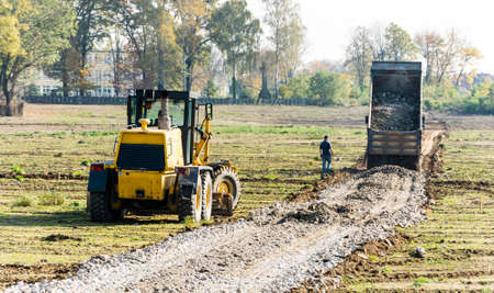Niedomice, Poland - October 19, 2017: Grader and lorry dump material for road construction.のeditorial素材